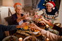 A group of people celebrating, raising their glasses together at a festive dinner table filled with food and candles. 